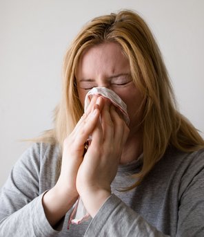 Eine erkältete Frau putzt sich die Nase