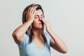 Eine Frau hat Kopfschmerzen und Schnupfen