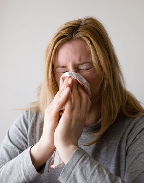 Eine erkältete Frau putzt sich die Nase