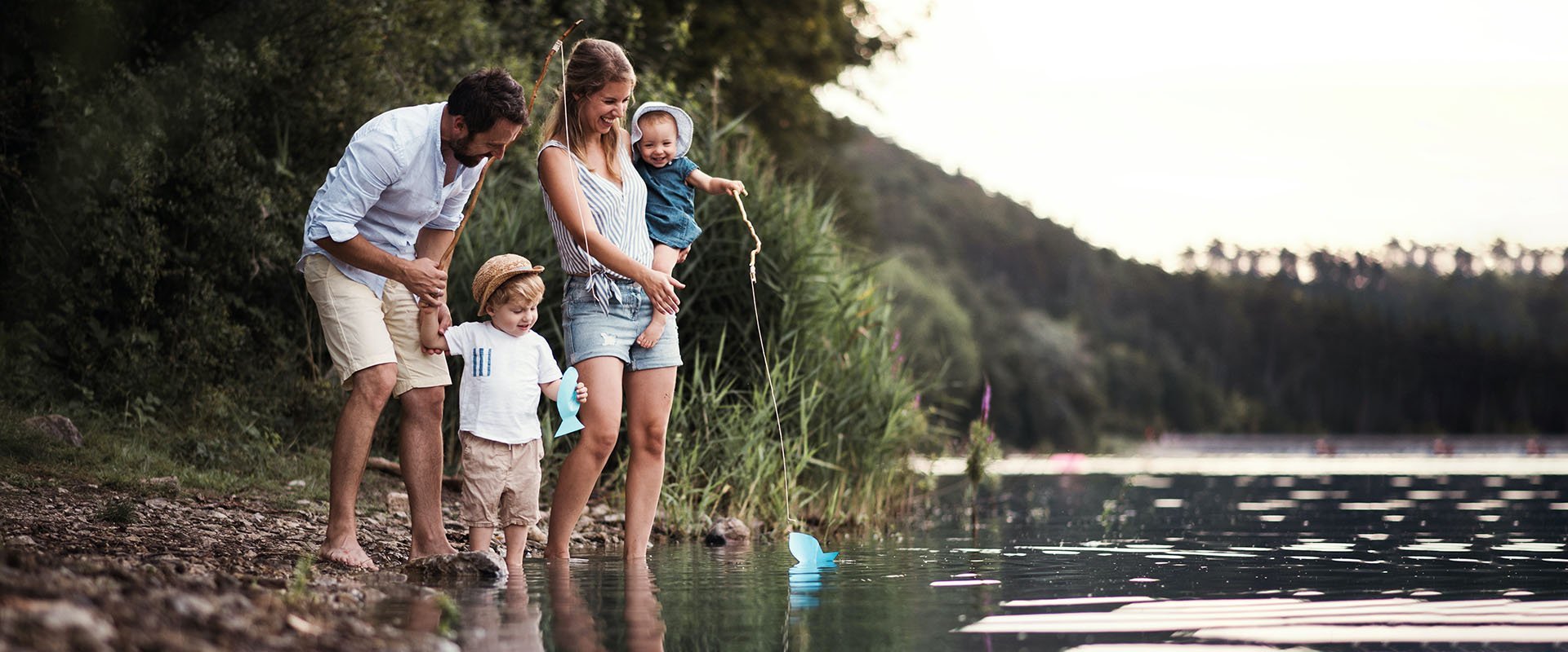 Eine Familie steht mit den Füßen im Wasser eines Sees.